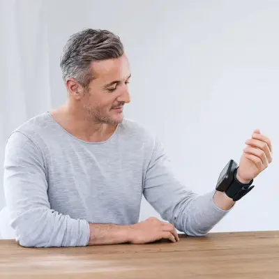 Person using the NovaMedicPRO Blood Pressure Monitor at home to check blood pressure readings on a digital wrist monitor with an easy-to-read LED display.